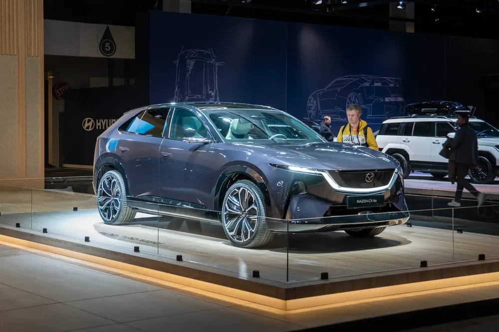 Le SUV Mazda CX-60 exposé dans un salon automobile moderne avec un éclairage accentué.