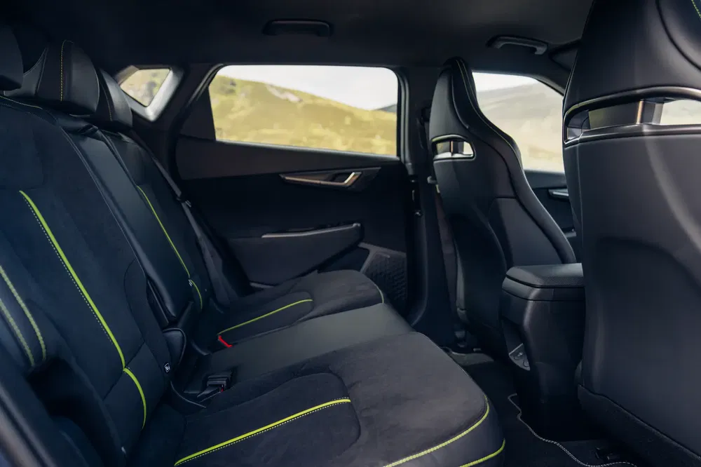 Intérieur de voiture, sièges arrière en tissu noir avec coutures vertes, design moderne et spacieux.
