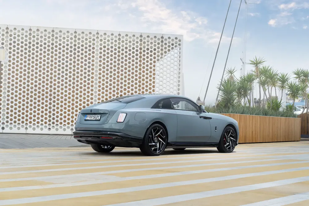 Rolls-Royce Spectre en arrière-plan architectural moderne et palmiers, ambiance luxueuse.