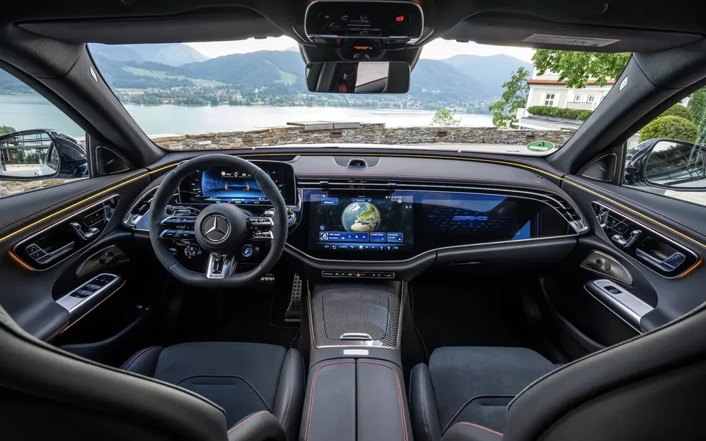 Intérieur d'une Mercedes avec tableau de bord numérique, vue sur un lac pittoresque.