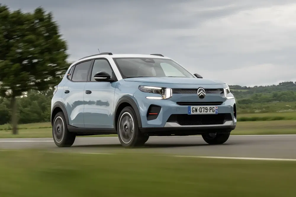 La Citroën C3 Aircross bleu sur route de campagne avec ciel nuageux.