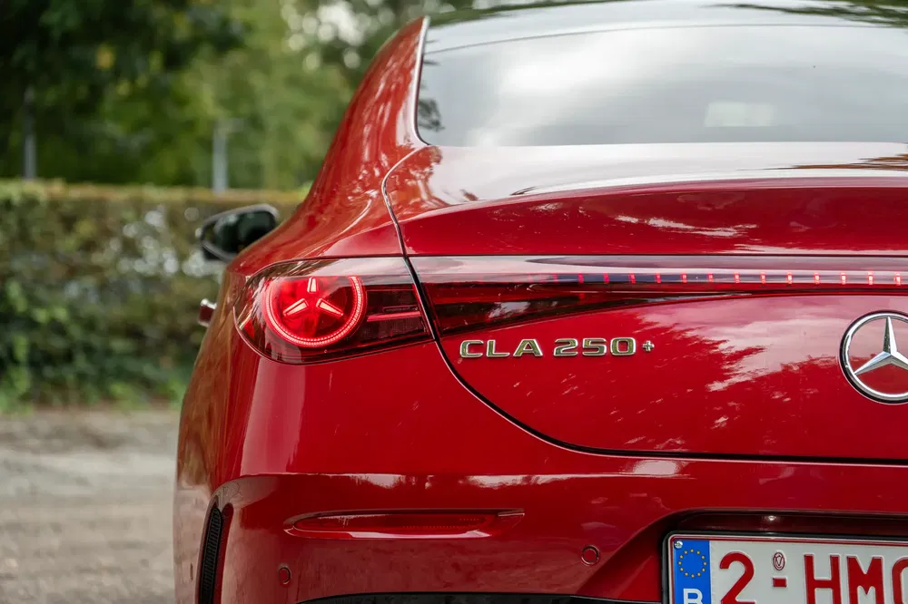 Achteraanzicht van een rode Mercedes CLA 250 met moderne LED-verlichting en Belgische nummerplaat.