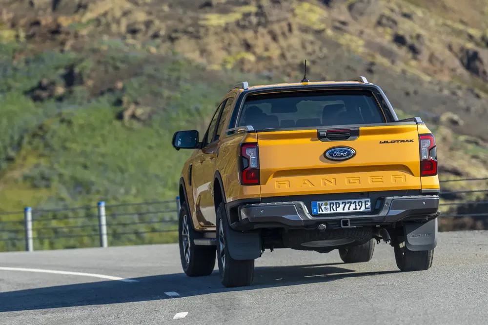Gele Ford Ranger Wildtrak op bergweg, ideaal voor buitenavonturen.