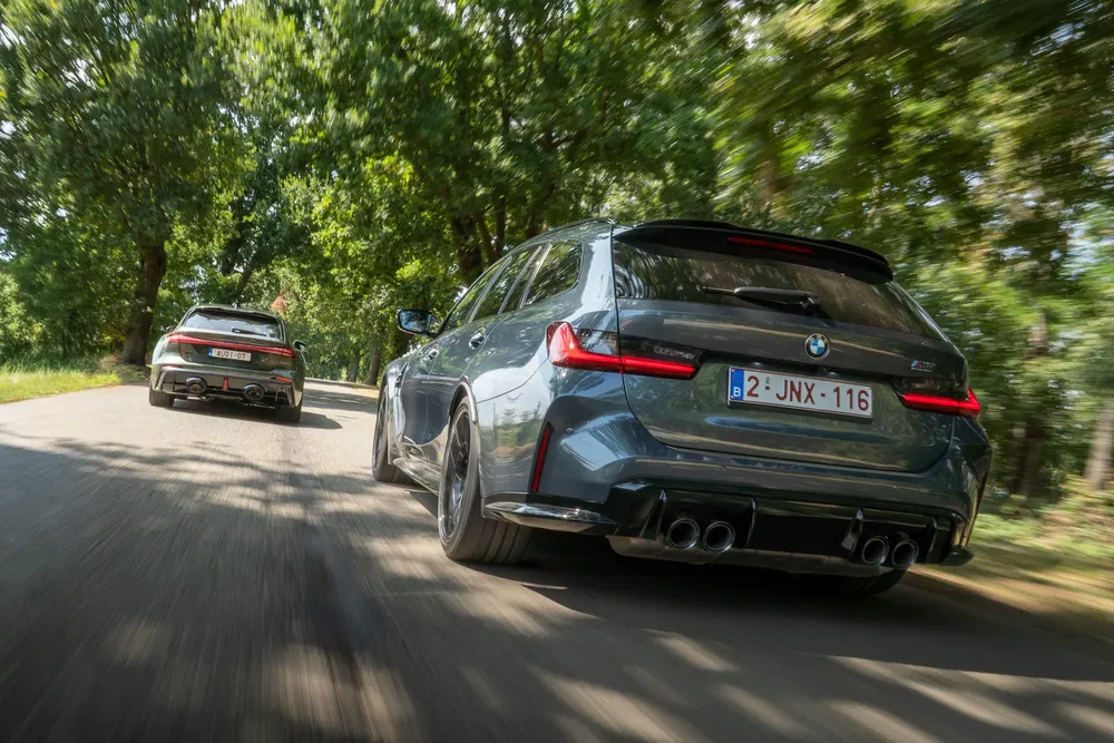 Twee BMW-auto's rijden op een boomrijke weg, sportief vakmanschap benadrukkend.