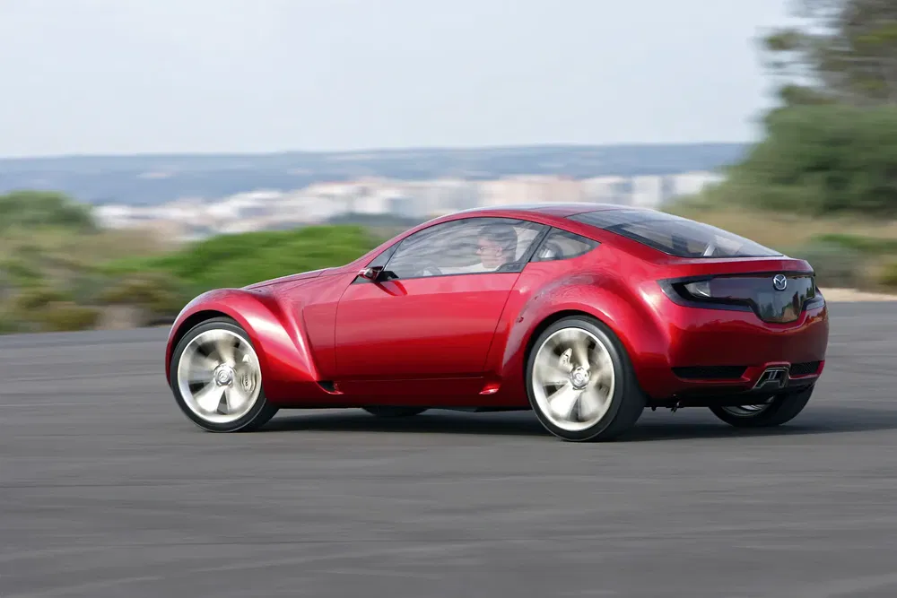 Mazda RX-8 rouge sport roulant rapidement sur route, conception élégante et dynamique.
