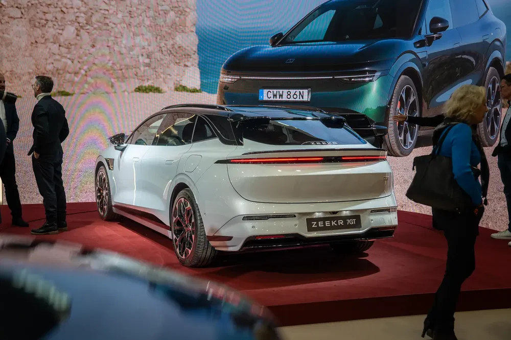 Voiture électrique Zeekr 001 exposée dans un salon automobile avec affichage en arrière-plan.