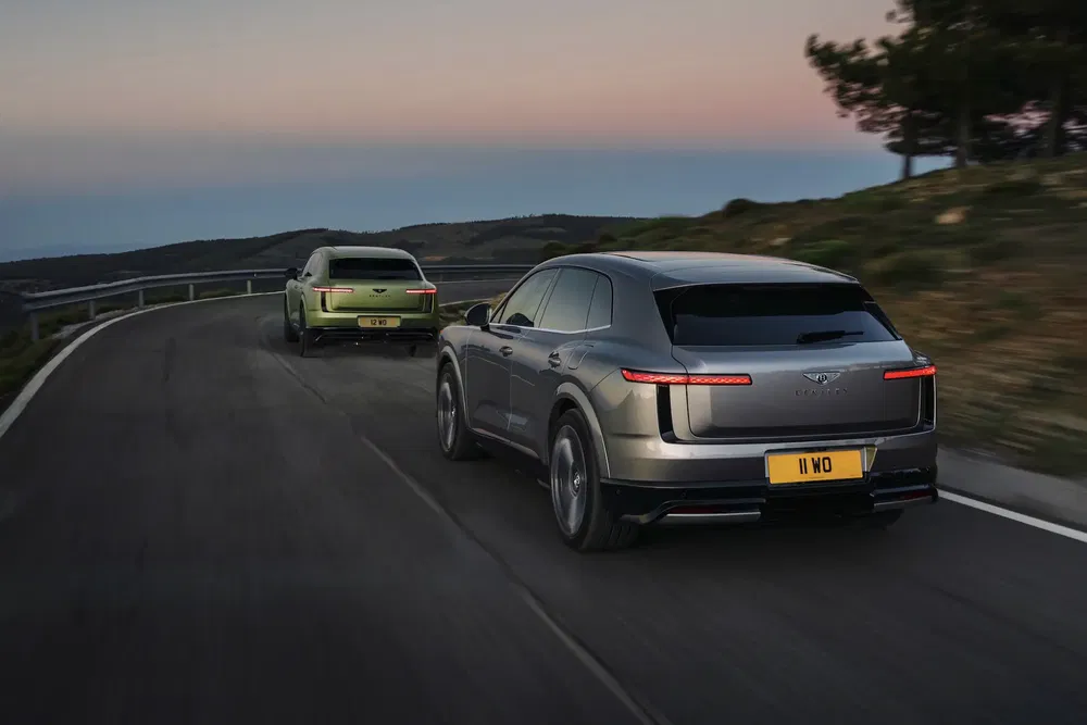 SUVs Lotus Eletre roulent sur une route sinueuse au coucher du soleil, paysage montagneux.