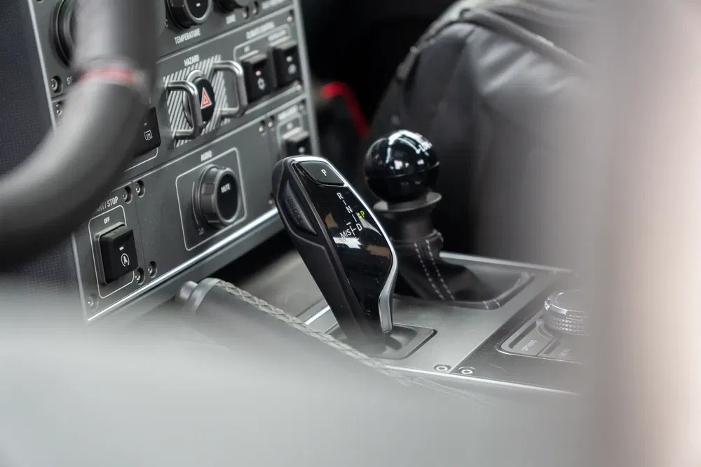 Moderne BMW-versnellingspook met digitale indicatoren in autointerieur.
