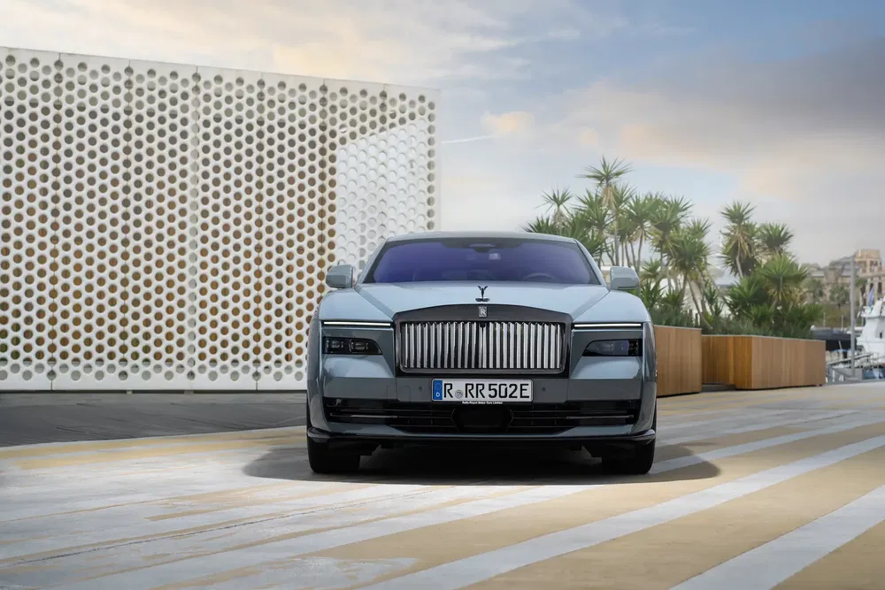 Rolls-Royce Spectre électrique stationnée devant un mur design au bord de la mer.