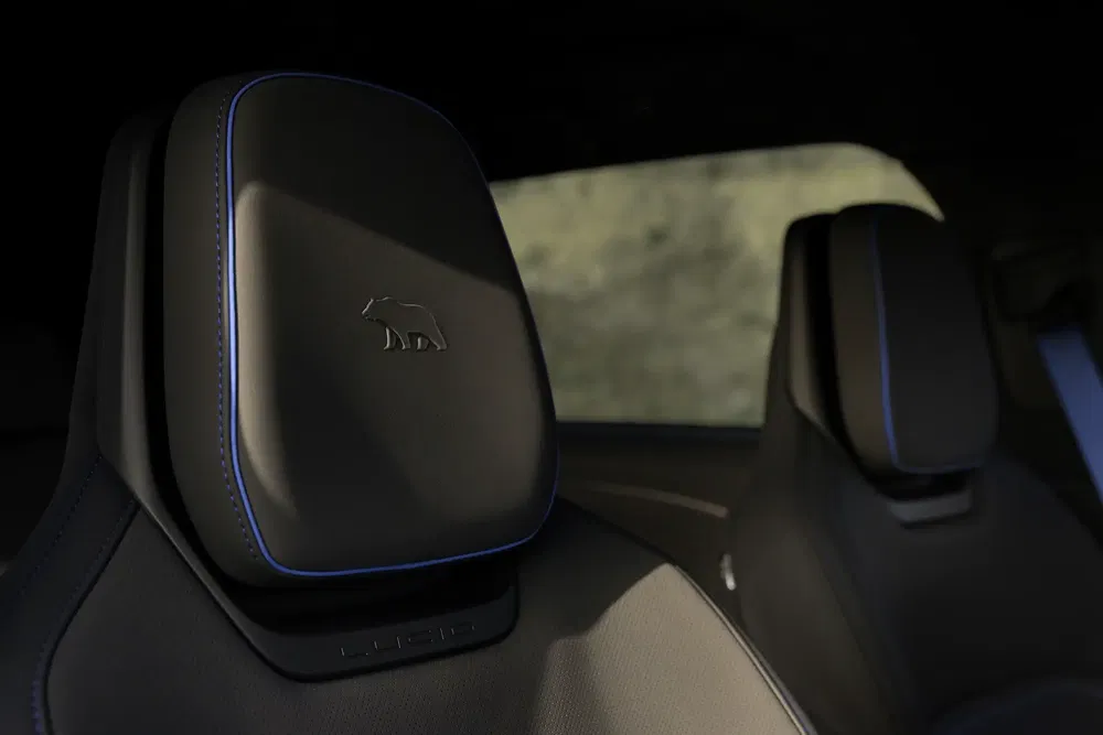 Lucid Air hoofdsteun met iconisch geborduurd berenlogo, stijlvolle blauwe stiksels.