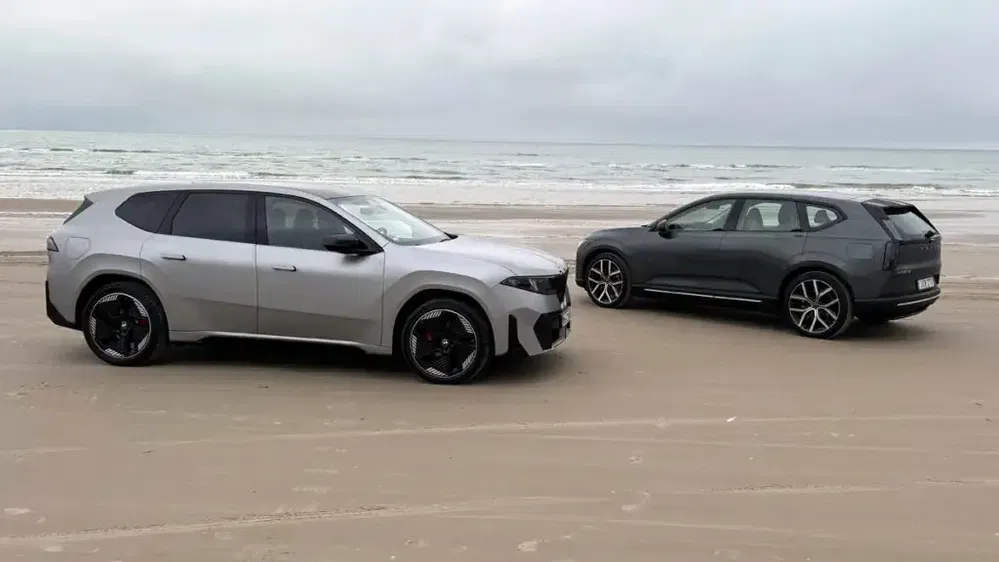 Deux SUV Zeekr 001 garés sur une plage, mer en arrière-plan, temps nuageux.