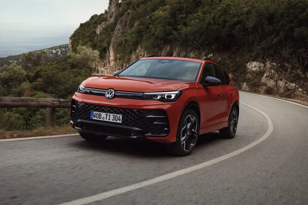 Volkswagen Tiguan rouge sur route sinueuse en montagne, séduction et performance.