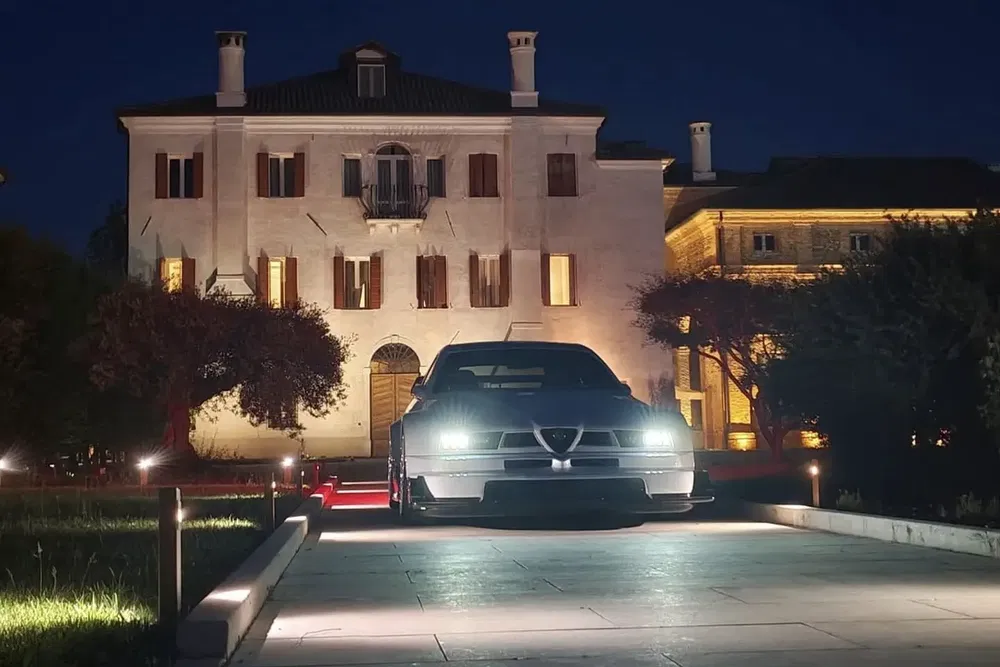 Alfa Romeo devant un manoir illuminé la nuit, style élégant et ambiance luxueuse.