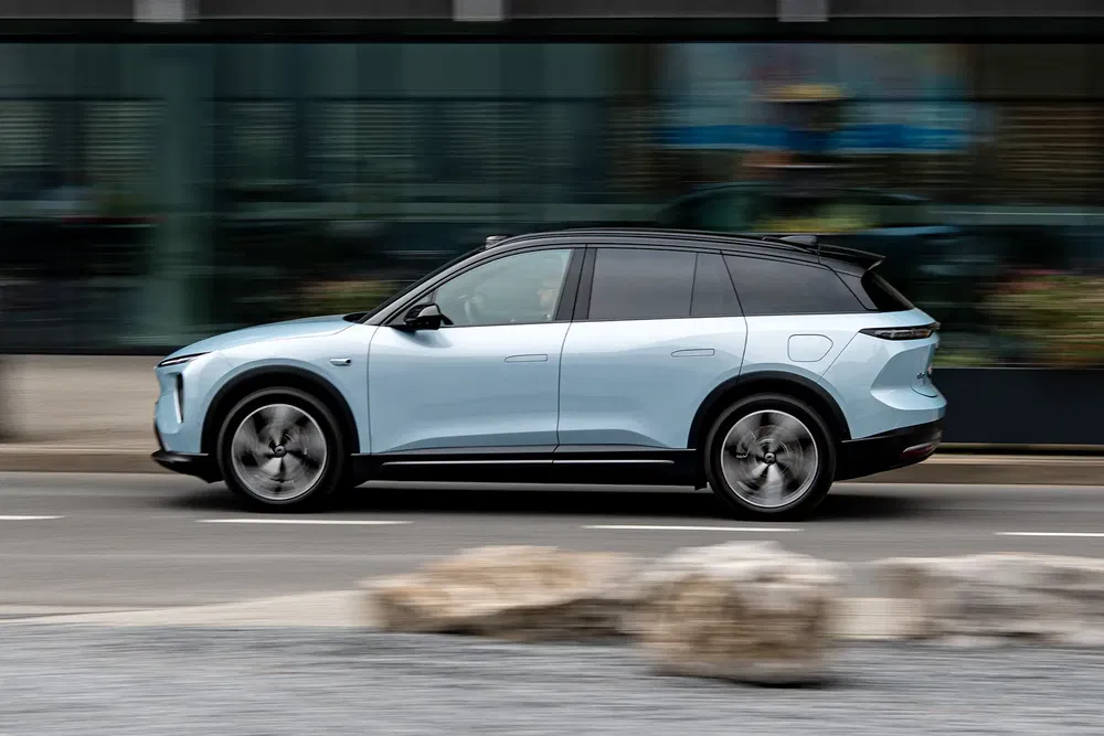 Blauwe NIO ES8 elektrische auto in beweging op een stedelijke weg.