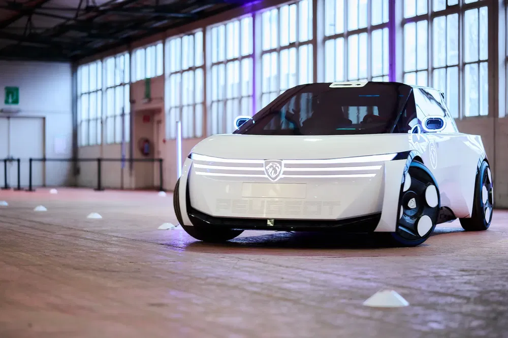 Concept-car Peugeot futuriste exposé dans un showroom industriel lumineux.