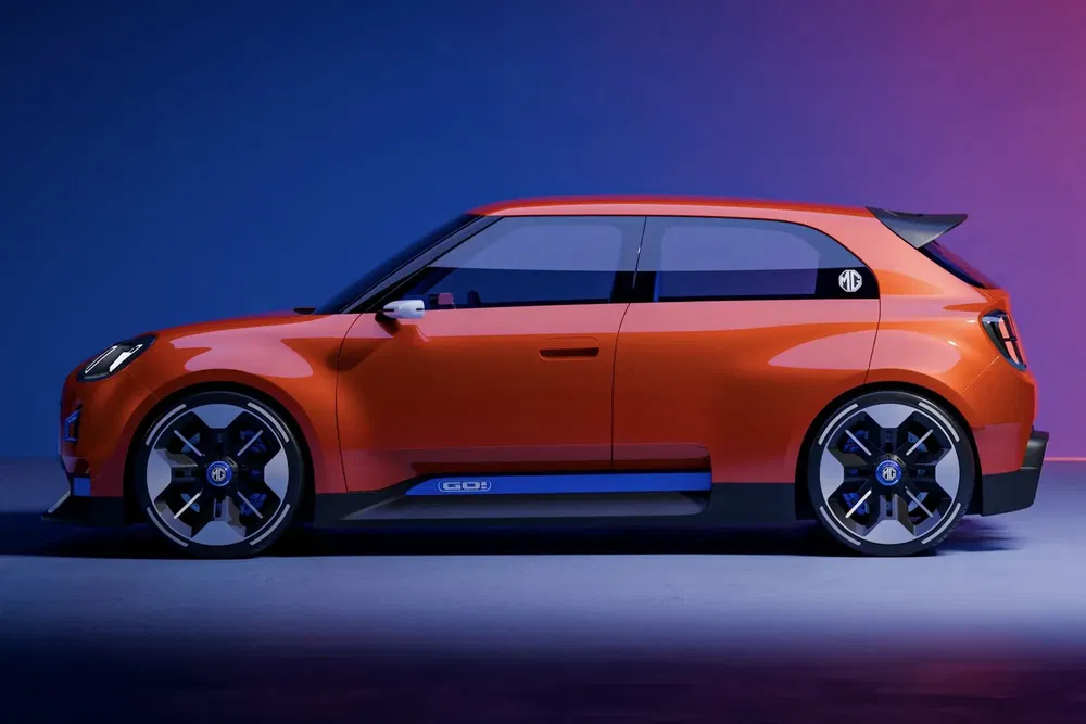 {"fr":"Concept car MG hatchback orange élégant sur fond coloré, jantes noires et toit noir.","nl":"Stijlvolle oranje MG hatchback conceptauto op kleurrijke achtergrond, zwarte velgen en dak."}