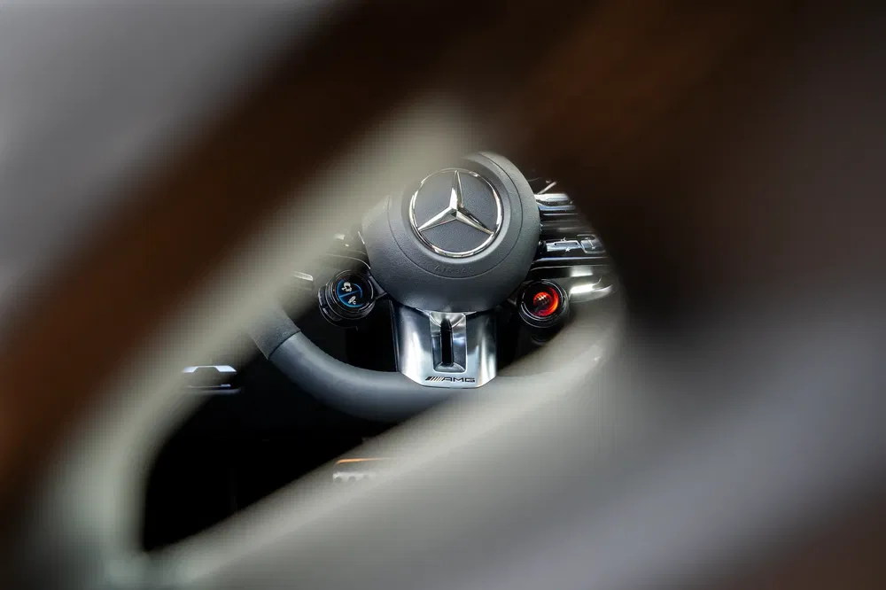 Volant Mercedes-Benz AMG vu à travers une ouverture, accent sur le logo étoile.