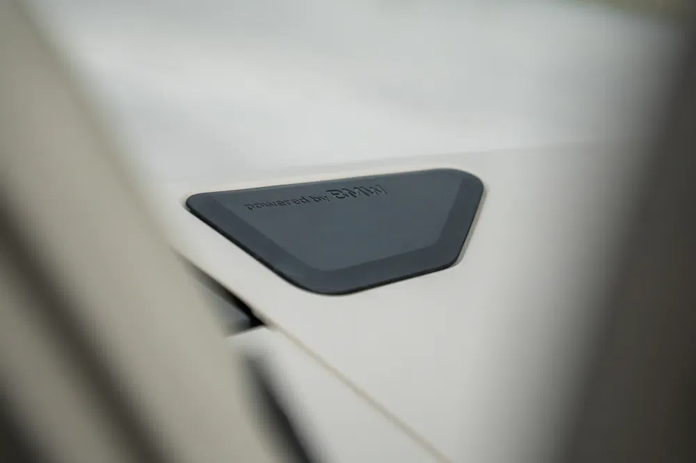 Detail van 'powered by BMW'-badge op de motorkap van een witte luxe auto.