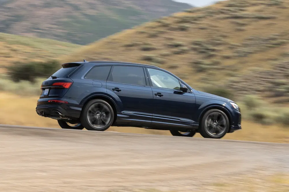 Audi Q7 bleu sur route de montagne en mouvement rapide.