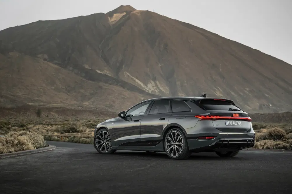 Audi A6 e-tron électrique sur route de montagne, arrière-plan montagneux.