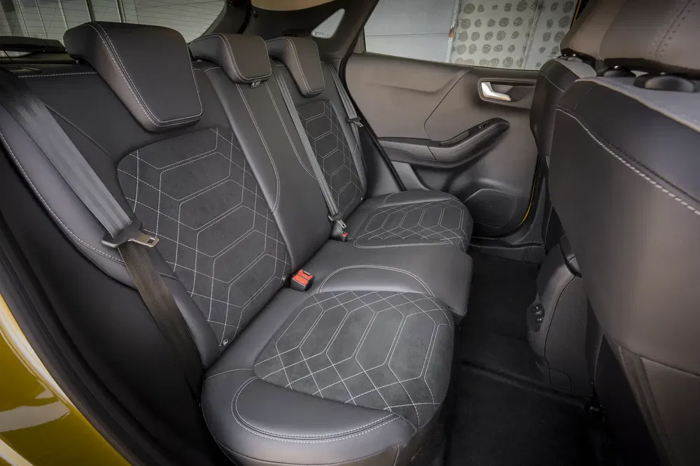 Intérieur arrière de voiture avec sièges en cuir noir et coutures contrastées.