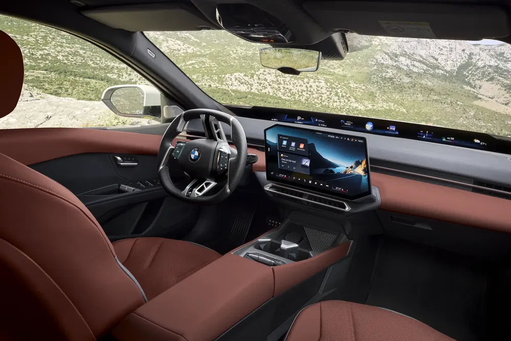 Intérieur moderne d'une BMW avec tableau de bord numérique et sièges en cuir brun.