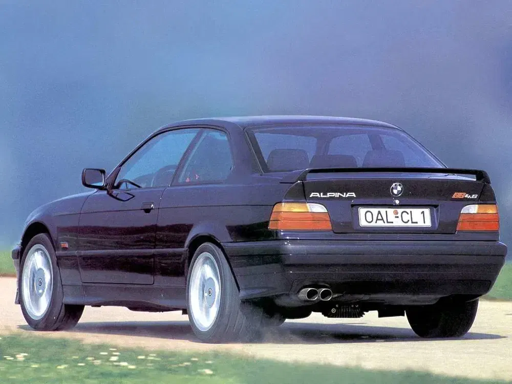 Voiture sportive BMW Alpina E36 noire avec plaque OAL-CL1 et double sortie d'échappement.