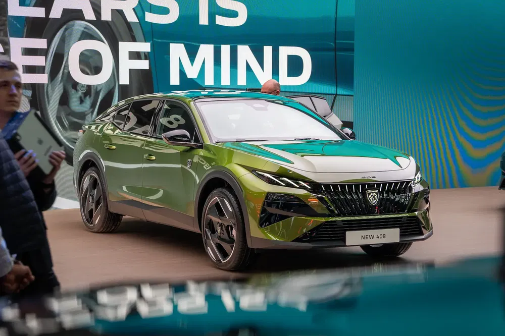 Peugeot 408 vert, design moderne, présenté dans un salon automobile.