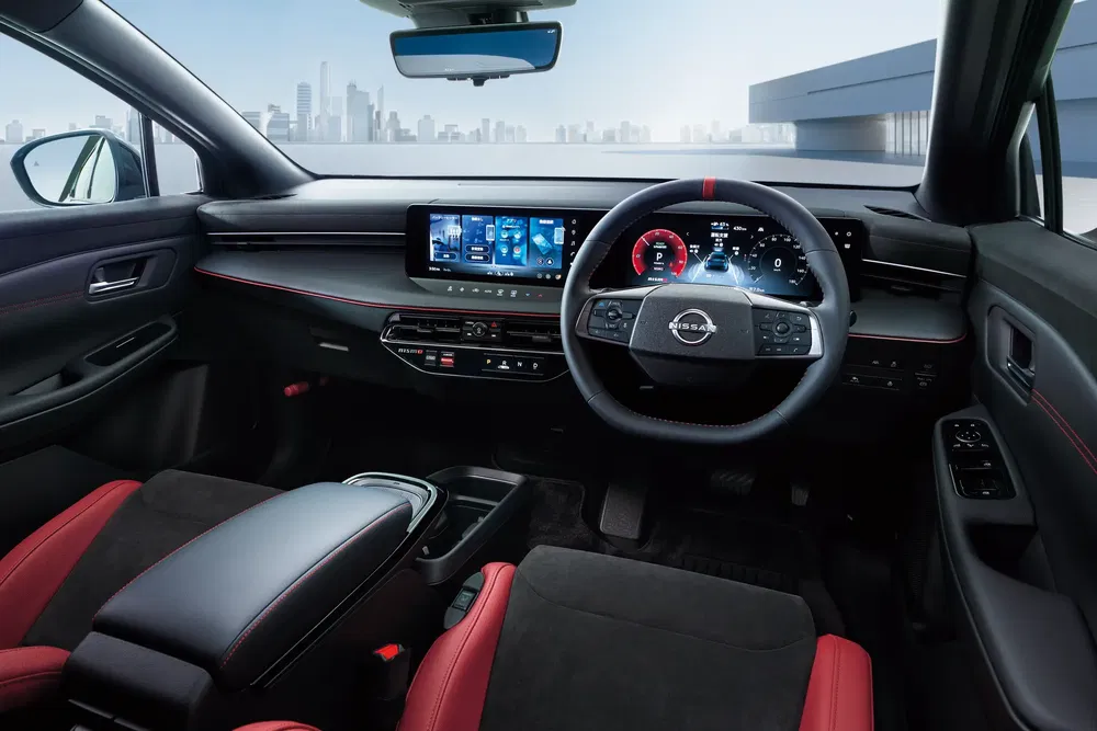 Habitacle moderne de la Nissan avec écran tactile, volant numérique, sièges sport rouges.