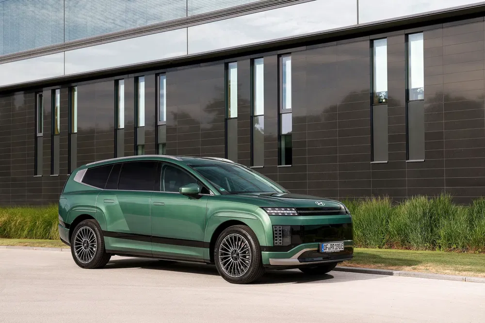 SUV électrique Hyundai Ioniq 7 vert devant bâtiment moderne avec fenêtres verticales.