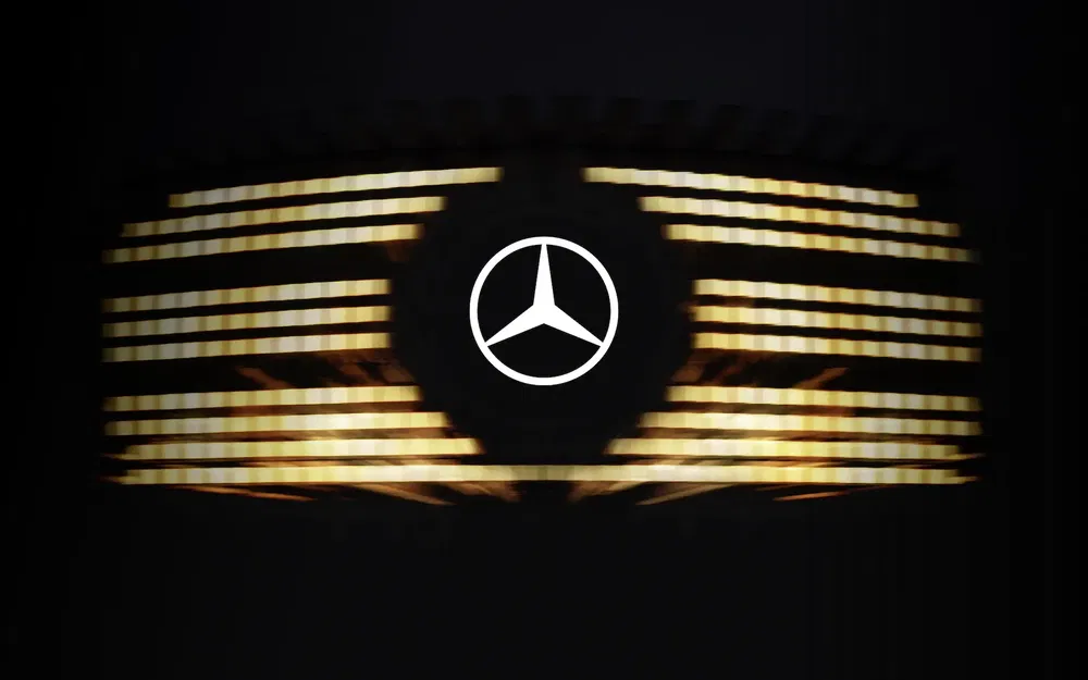 {"fr":"Logo Mercedes-Benz avec phares LED dorés illuminés en arrière-plan sombre.","nl":"Mercedes-Benz-logo met verlichte gouden LED-koplampen op een donkere achtergrond."}