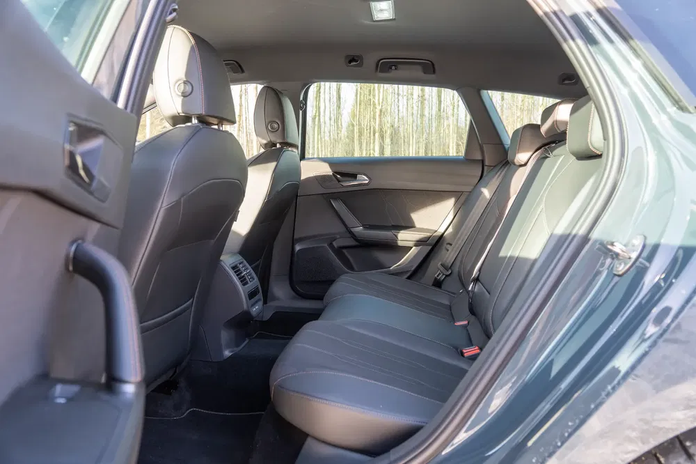 Ruim interieur van een Volkswagen met zwarte lederen achterstoelen en stijlvolle armleuningen.
