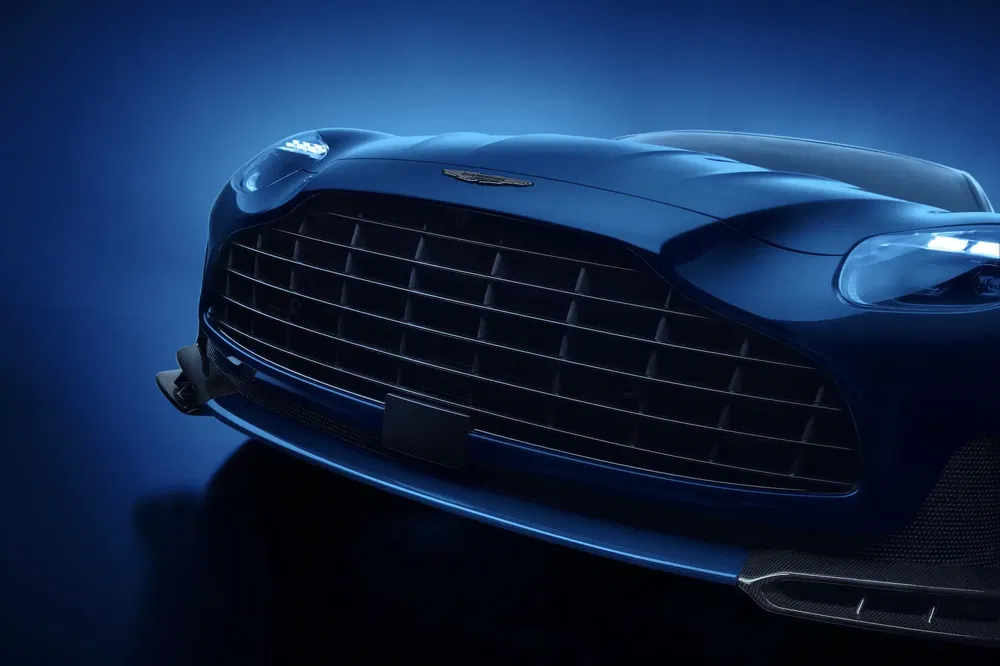 Gros plan sur la calandre d'une Aston Martin bleue sous éclairage bleu.