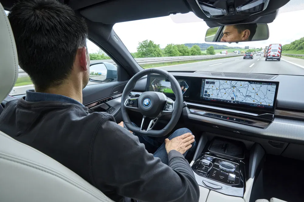 Conducteur détendu dans une BMW avec système de navigation avancé sur l'autoroute.