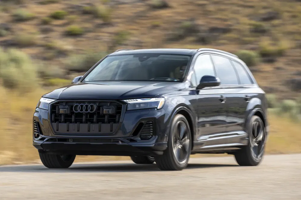 Audi Q7 gris foncé roulant sur une route déserte, performance SUV moderne.