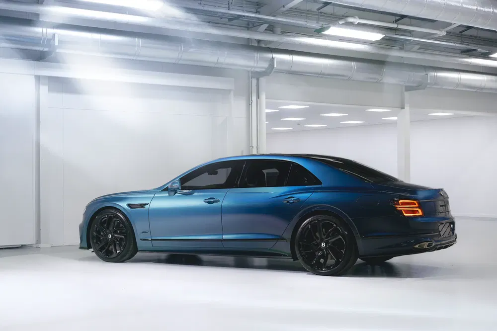 Bentley Flying Spur bleu, stationné dans un garage moderne et bien éclairé.