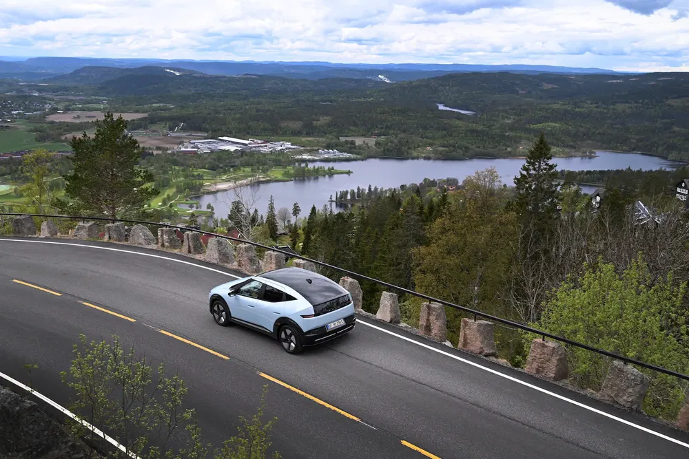 Hyundai Ioniq 5 roulant sur une route sinueuse avec vue sur un paysage vallonné et boisé.