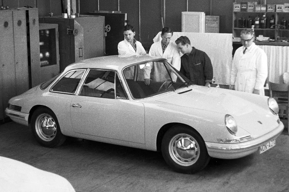 Prototypage Porsche 911 vintage dans un atelier avec ingénieurs autour.