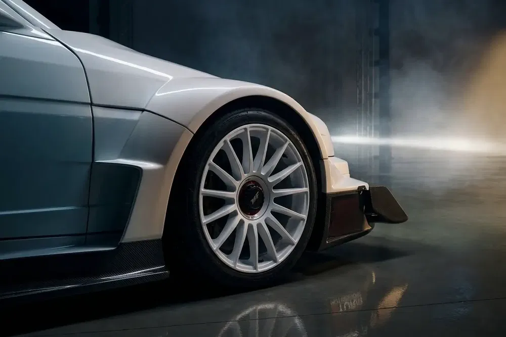 Voiture de sport BMW, gros plan sur le pneu et le pare-chocs agressif en lumière diffuse.
