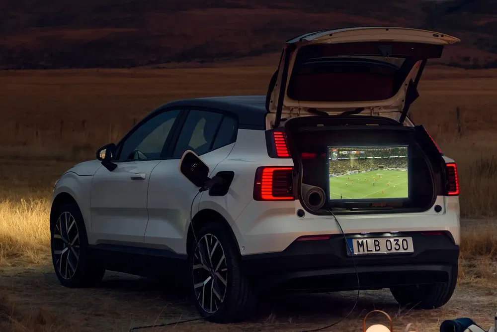 Voiture électrique Volvo XC40 avec téléviseur dans le coffre, paysage désertique en arrière-plan.