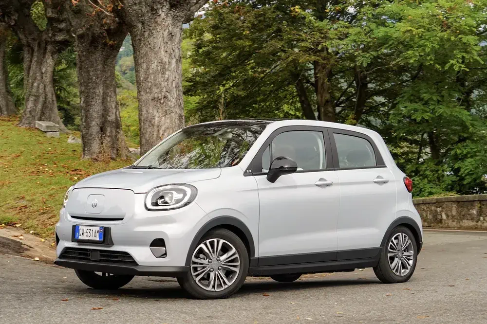 Voiture électrique Dr 1.0 blanche garée dans un parc verdoyant.