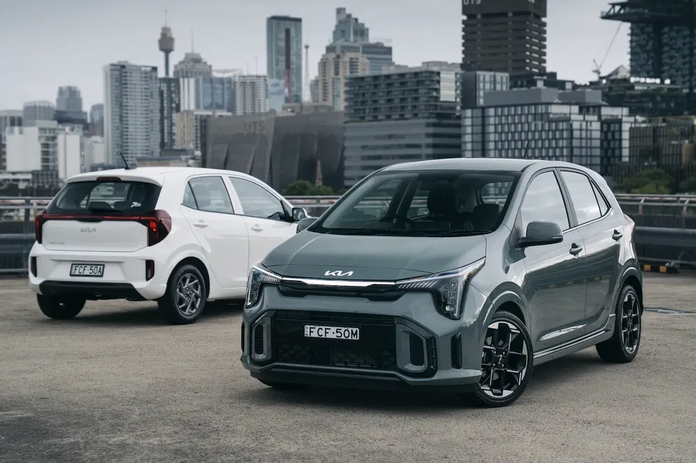 Deux Kia Picanto modernes garées avec vue urbaine en arrière-plan.