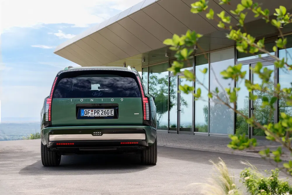 Hyundai Ioniq 7 vert stationné devant une maison moderne avec vue panoramique.