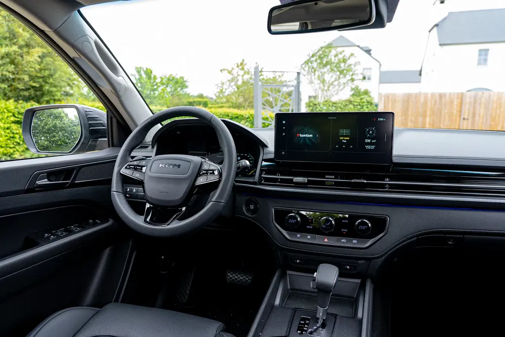 Intérieur d'un véhicule KIA moderne avec tableau de bord numérique et volant ergonomique.