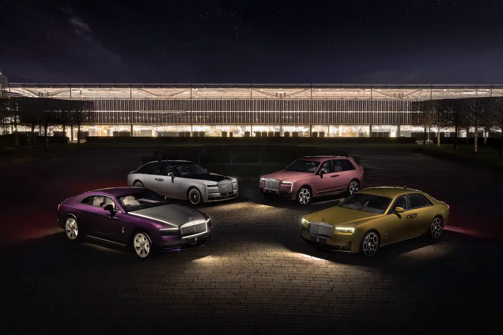 Quatre voitures Rolls-Royce colorées devant un bâtiment moderne de nuit.