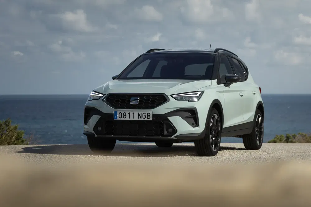 SUV Seat Arona geparkeerd voor de zee onder een bewolkte hemel.