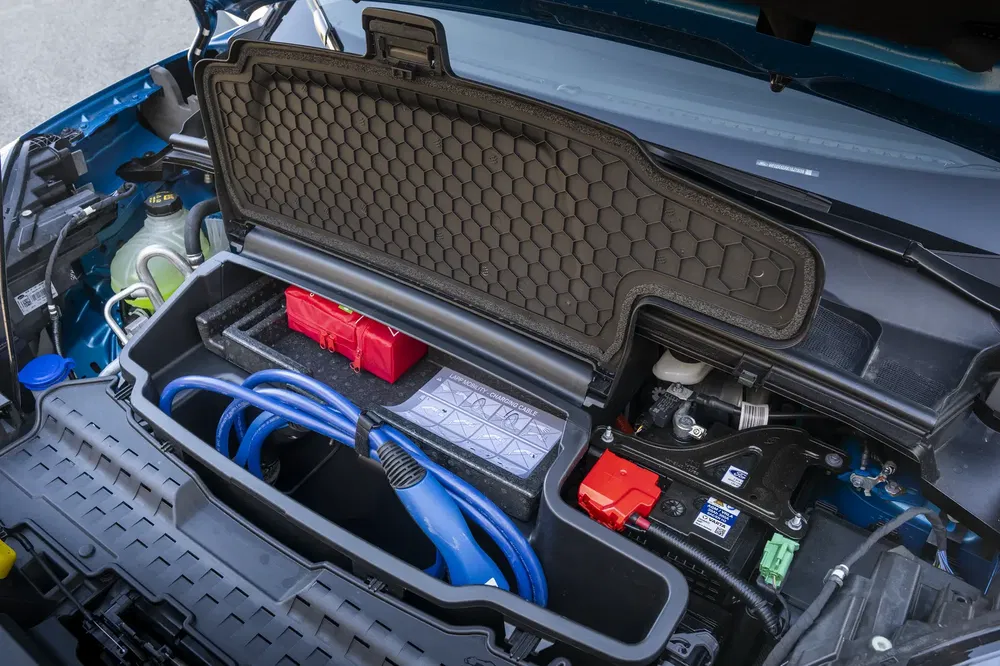 Coffre avant d'une voiture électrique, avec câbles de recharge et compartiments organisés.