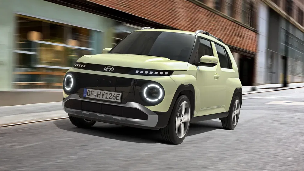 Hyundai elektrische compacte auto rijdt in stedelijke omgeving, modern ontwerp en opvallende koplampen.