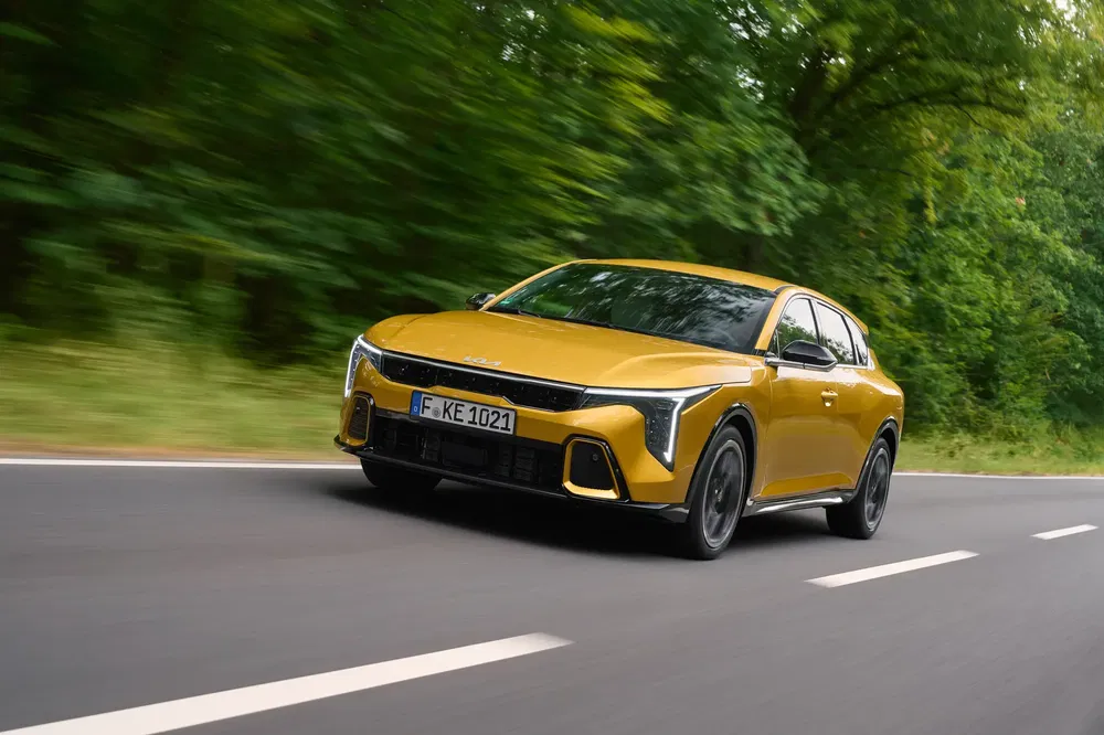 Peugeot 408 dorée roulant sur une route bordée de verdure.