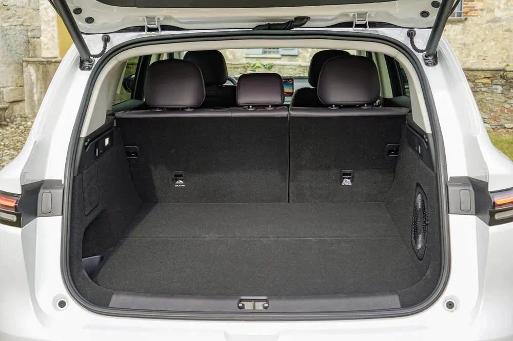 Ruime kofferbak van een witte SUV met neerklapbare stoelen en geïntegreerd audiosysteem.
